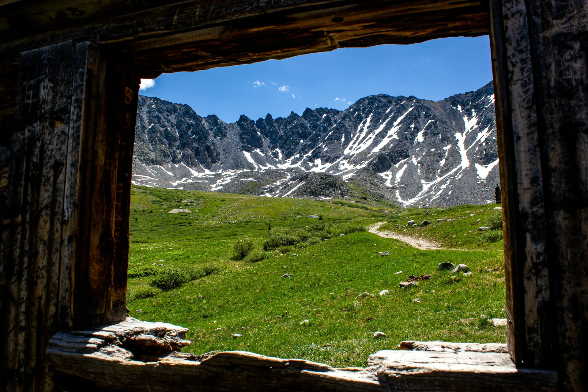 Scenic view of mountains through an old cabin window in Frisco, Colorado with clear skies.