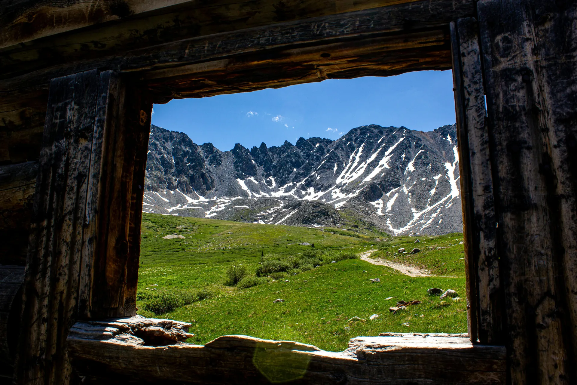 Framed view of rugged Rocky Mountains through a rustic cabin window in Frisco, Colorado.